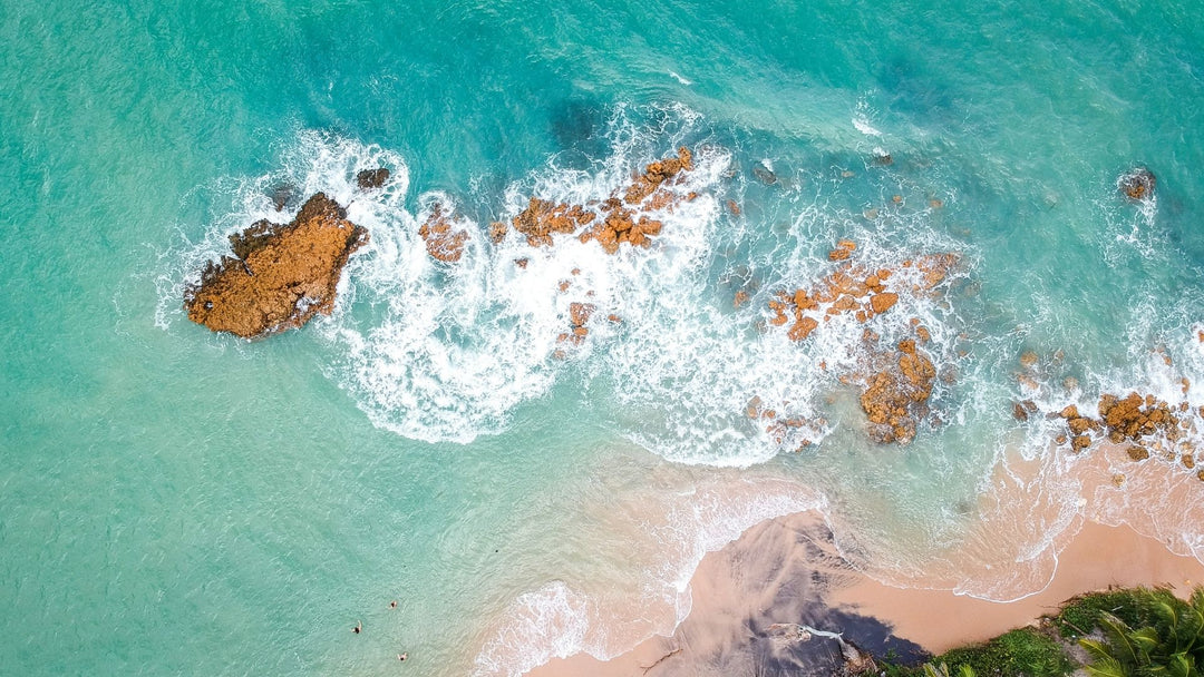 Aqua colored ocean with rocks, reef, sand, and beach