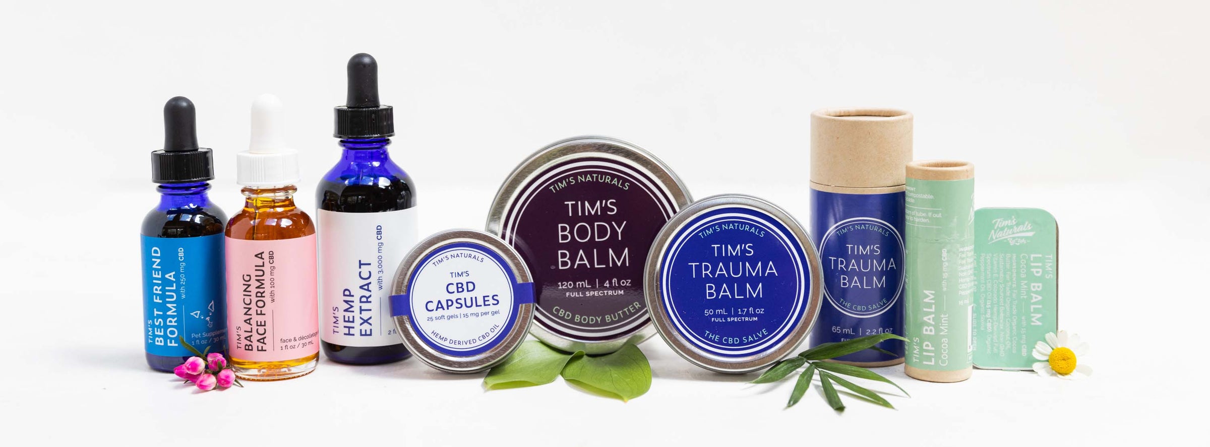 Tim's Best Friend Formula bottle, Tim's Balancing Face Formula bottle, Tim's Hemp Extract bottle, Tim's CBD Capsules tin, Tim's Body Balm purple tin, Tim's Body Balm blue tin, Tim's Body Balm kraft paper tube, Tim's Lip Balm with ingredients and white bac